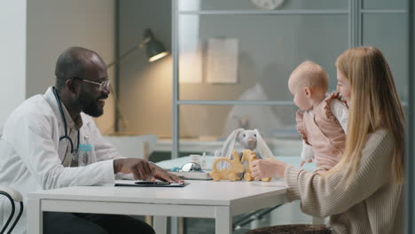 pediatrician giving consultation to woman with baby in clinic