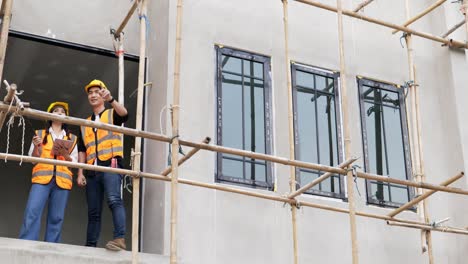 4k low angle view . a young male and female asian civil engineers holding a tablet and working together at balcony .