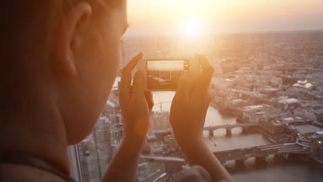 Tourist-taking-photograph-of-sunset-in-london-skyline--view-from-The-Shard