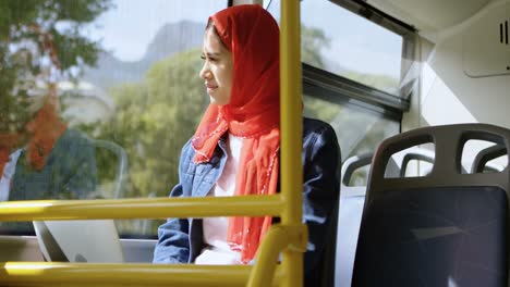 woman in hijab looking through the window while using laptop 4k