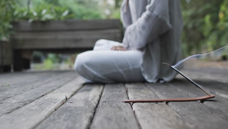 Low-section-of-biracial-woman-practicing-yoga-in-sunny-garden,-slow-motion