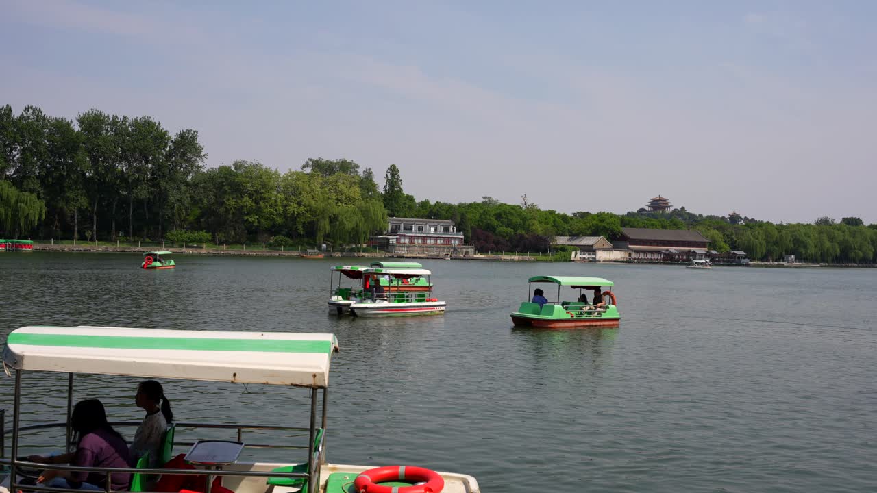 Touristic boats on the lake in Beihai Park under clear skies in Beijing, China