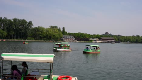 touristic boats on the lake in beihai park under clear skies in beijing, china