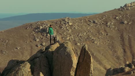 Un-Excursionista-Solitario-Se-Encuentra-En-La-Cima-De-Una-Montaña-Con-Un-Dron-De-Paralaje-Lento.