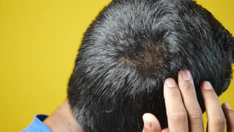 teenage boy scratching head against black background