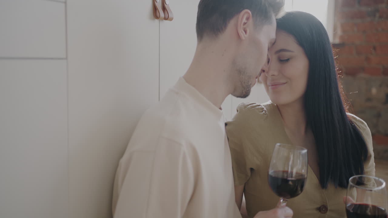 una pareja disfrutando del vino en la cocina.