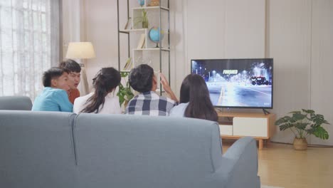 asian teenagers playing racing video game at home. team win and team lost