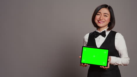 Asian-receptionist-holding-tablet-with-greenscreen-on-camera,