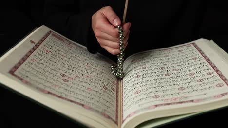 footage of a muslim person with a prayer beads and an open quran, the person is doing dhikr