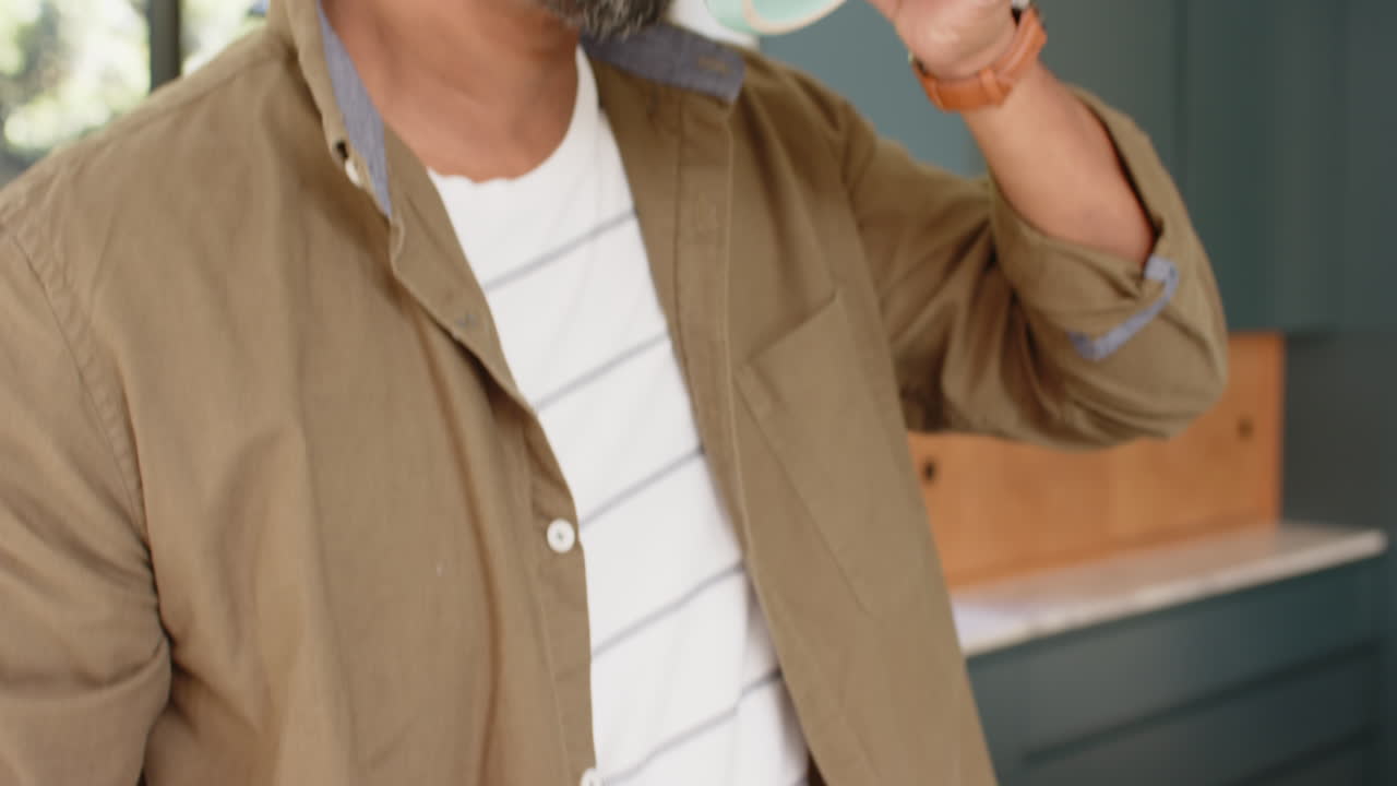 Holding smartphone, man talking on phone in casual outfit indoors