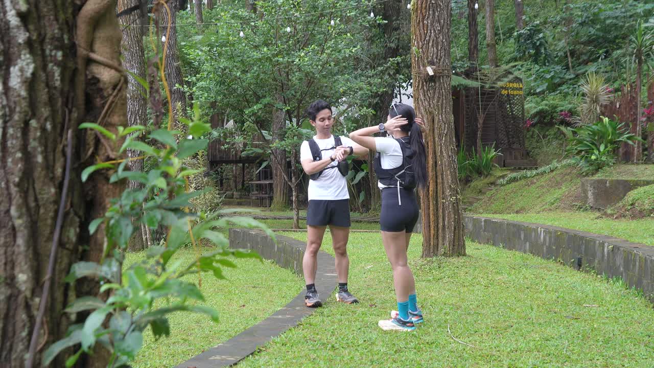Asian couple resting and talking during outdoor workout in forest trail