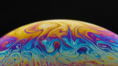 half circle a soap bubble surface multicolored in motion isolated on black background. vivid rainbow colors in weird and strange patterns. close up. slow motion