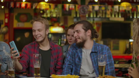 grupo de amigos jóvenes bebiendo y riendo en un bar