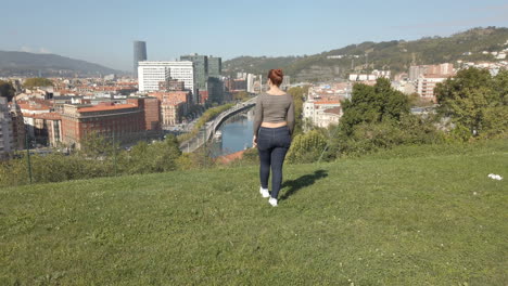 Scenic Cityscape View with Woman on Grassy Hill