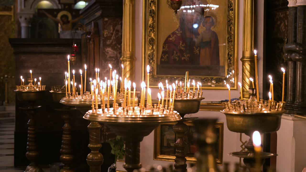 Votive candles flicker before a sacred icon inside St. Volodymyr's Cathedral in Kyiv, Ukraine. The warm candlelight creates a serene, spiritual atmosphere in the historic Orthodox landmark.