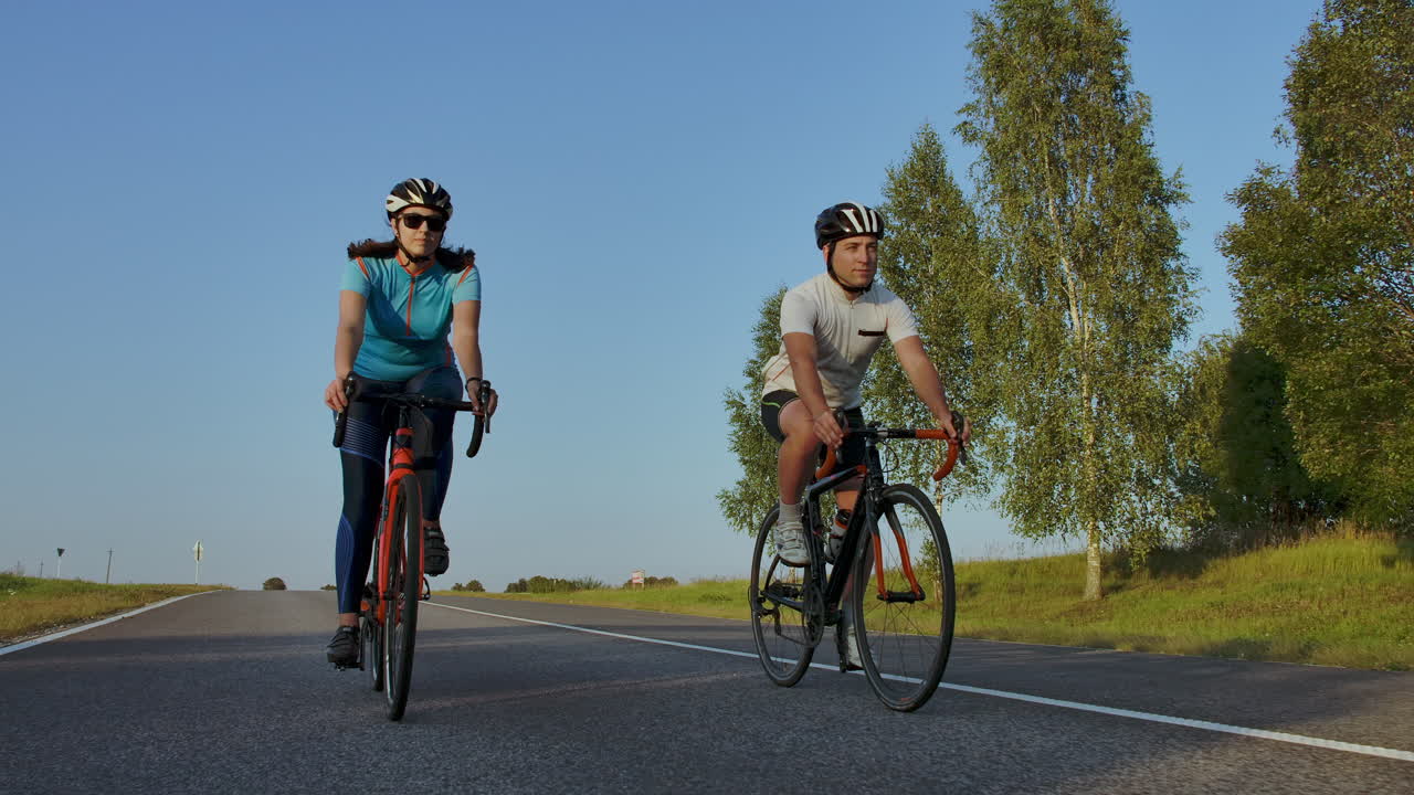 ciclista montando en bicicleta de carretera vista trasera. hombres en bicicleta pedaleando bicicleta de carretera en el parque de la ciudad. seguimiento de disparos de ciclistas en bicicleta de ruta al atardecer. atleta ciclista entrenamiento intensivo en bicicleta