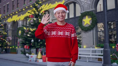 man waving in christmas decorated city street