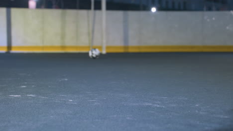 legs of soccer player kicking ball toward goal post during night training session on outdoor field, focus on movement, action, and precision with urban backdrop and bright stadium lighting