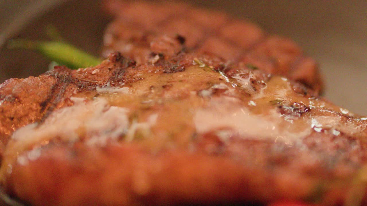 Close-up of butter melting over grilled steak, warm lighting, shallow depth, static camera