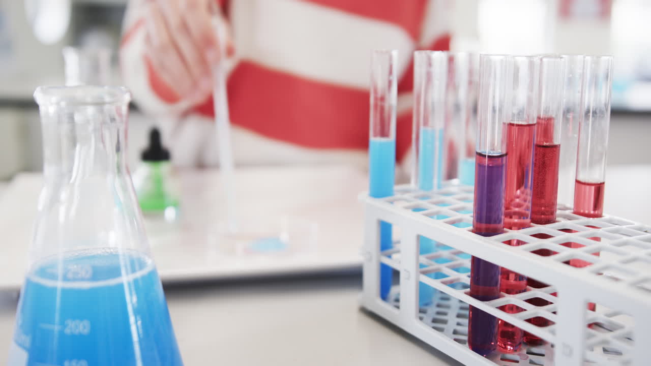 Young girl conducting colorful chemistry experiment with test tubes in science class, at school