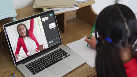 Schoolgirl-using-laptop-for-online-lesson-at-home,-with-her-school-friend-and-web-chat-on-screen