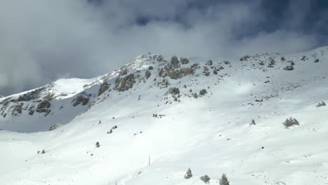 Aerial-drone-forward-moving-shot-of-over-people-going-up-the-mountain-slope-by-chairlift-at-Engelberg-Brunni-bahnen-along-the-Swiss-alps-in-Switzerland-on-a-cloudy-day