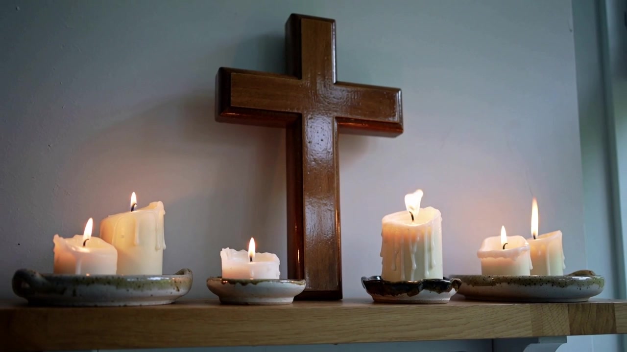 Zurückfahrende Kamera enthüllt Holzkreuz und Kerzen auf einem Regal zu Hause, Fensterlicht zeigend.
