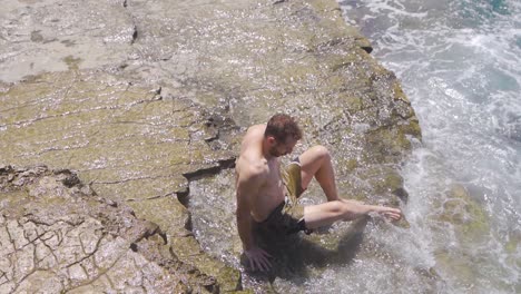 Young-man-sitting-on-the-beach.-Slow-Motion.