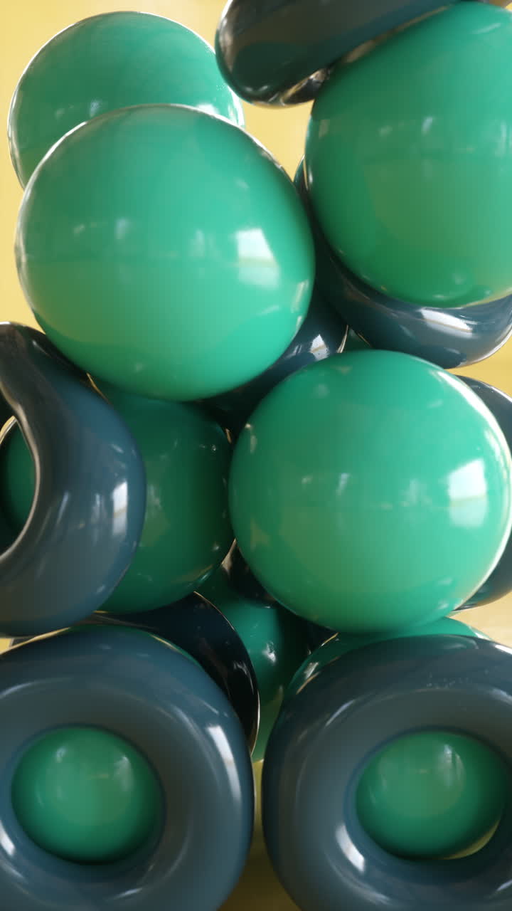 Rubber balls and rings falling in heap on yellow. Satisfying 3d animation. Vertical orientation