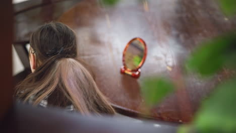 vista aérea de una joven con camisa a cuadros colocando un espejo y herramientas cosméticas en una mesa de madera, rodeada de exuberante vegetación. ambiente acogedor y natural con iluminación suave y una atmósfera relajada