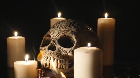 dólares en llamas con cuatro velas encendidas y un cráneo cerca sobre fondo negro