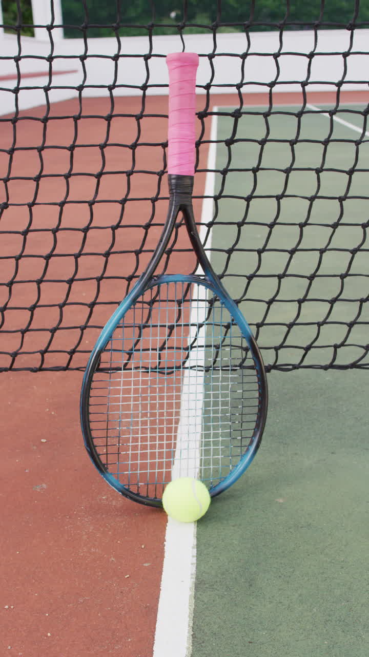 Vertical video of yellow tennis ball and racket on tennis court