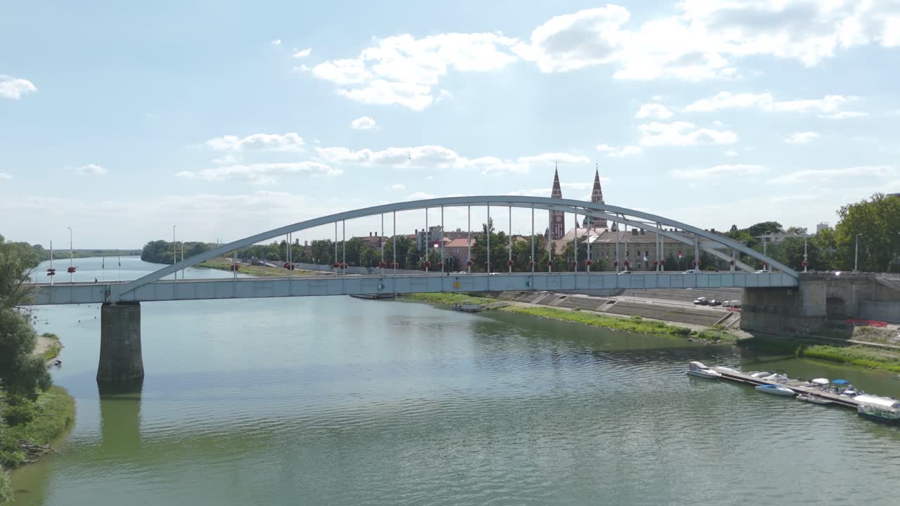 Beautiful low aerial orbit over the Tisza River revealing Szeged’s Belvárosi Bridge and the surrounding riverside landscape