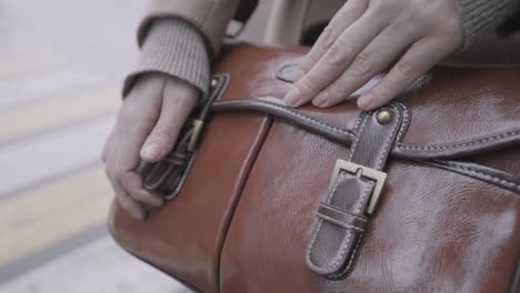 woman holding a brown leather crossbody bag