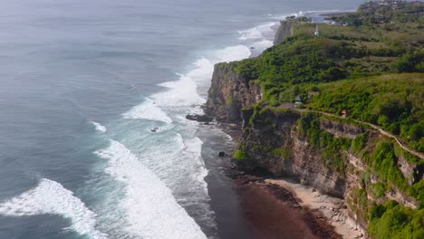slow aerial push-in of ocean waves by cliffs in uluwatu, indonesia