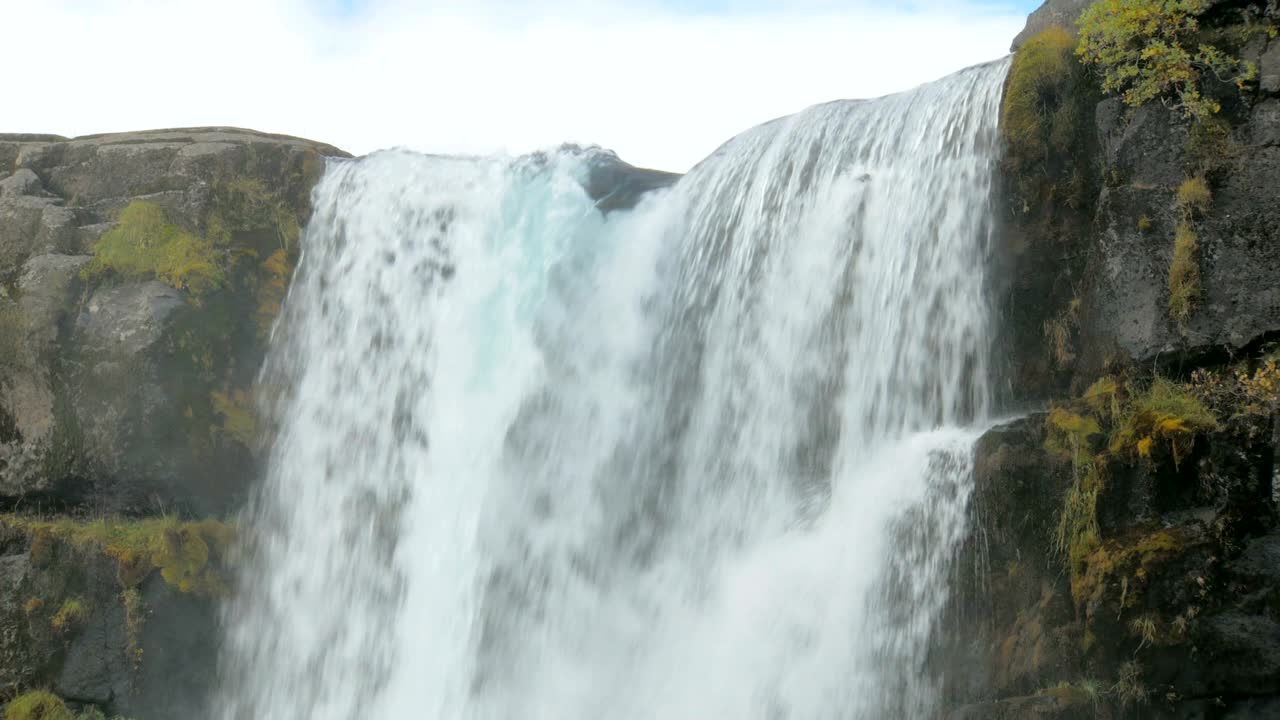 Kraftig flodstrøm falder fra basaltklipper, nærbillede af toppen af vandfaldet