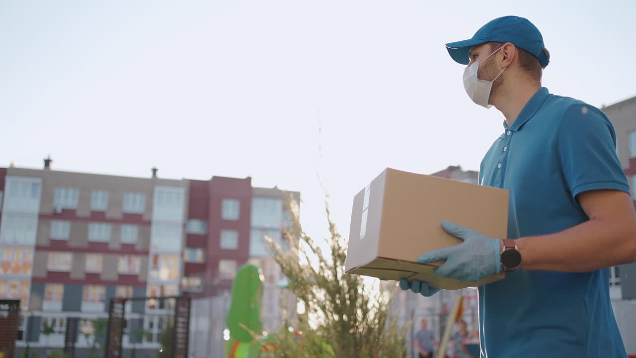un joven mensajero con una máscara protectora y guantes está entregando un paquete directamente a la casa de un cliente con seguridad. concepto de mensajero de entrega a domicilio comercio electrónico envío virus covid