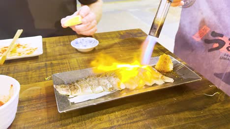 chef uses blowtorch to sear fish dish