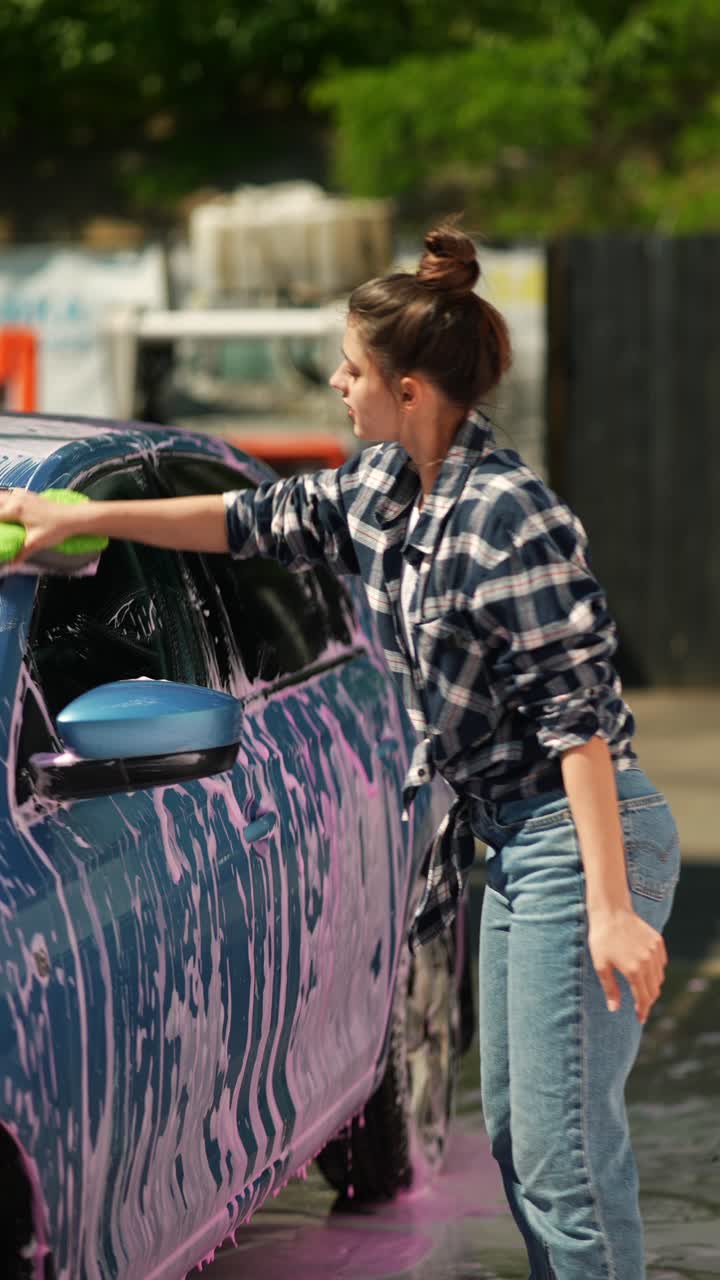 una mujer joven lavando su coche.