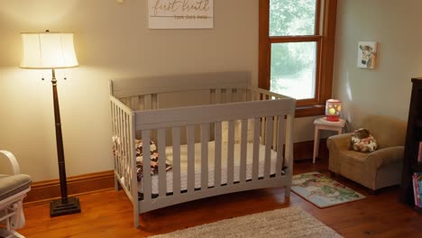 orbiting shot of a grey baby crib next to a lamp in a nursery