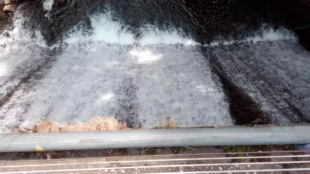 Pan left over cascading water flowing through small dam structure
