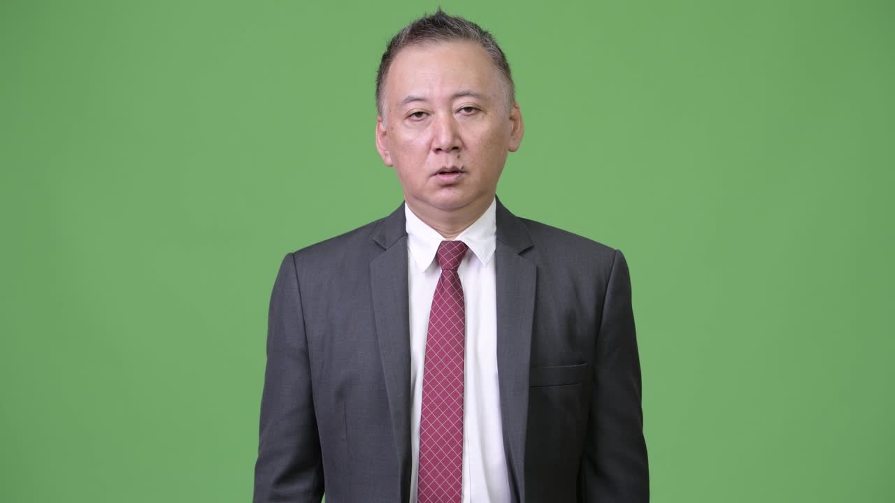 성숙한 일본인 사업가들이 엄지손가락을 내려놓는다.