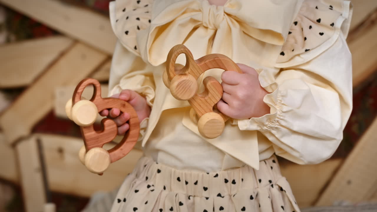 Little girl holding two wooden snail rolling toys. Ecological and sustainability concept