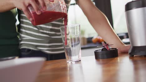 Midsection-of-diverse-male-couple-making-healthy-drink-together-in-kitchen