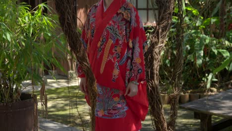 Peaceful-beautiful-latin-young-woman-wearing-Ryusou-okinawan-kimono-dress-at-Okinawa-world-Naha-Japan-japanese-garden-sunny-day