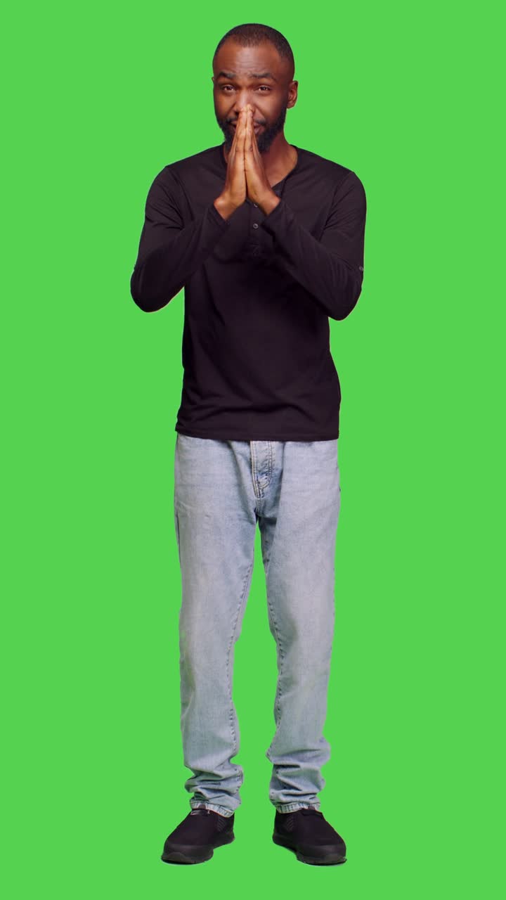Vertical video: Front view of male adult with belief praying to god on camera
