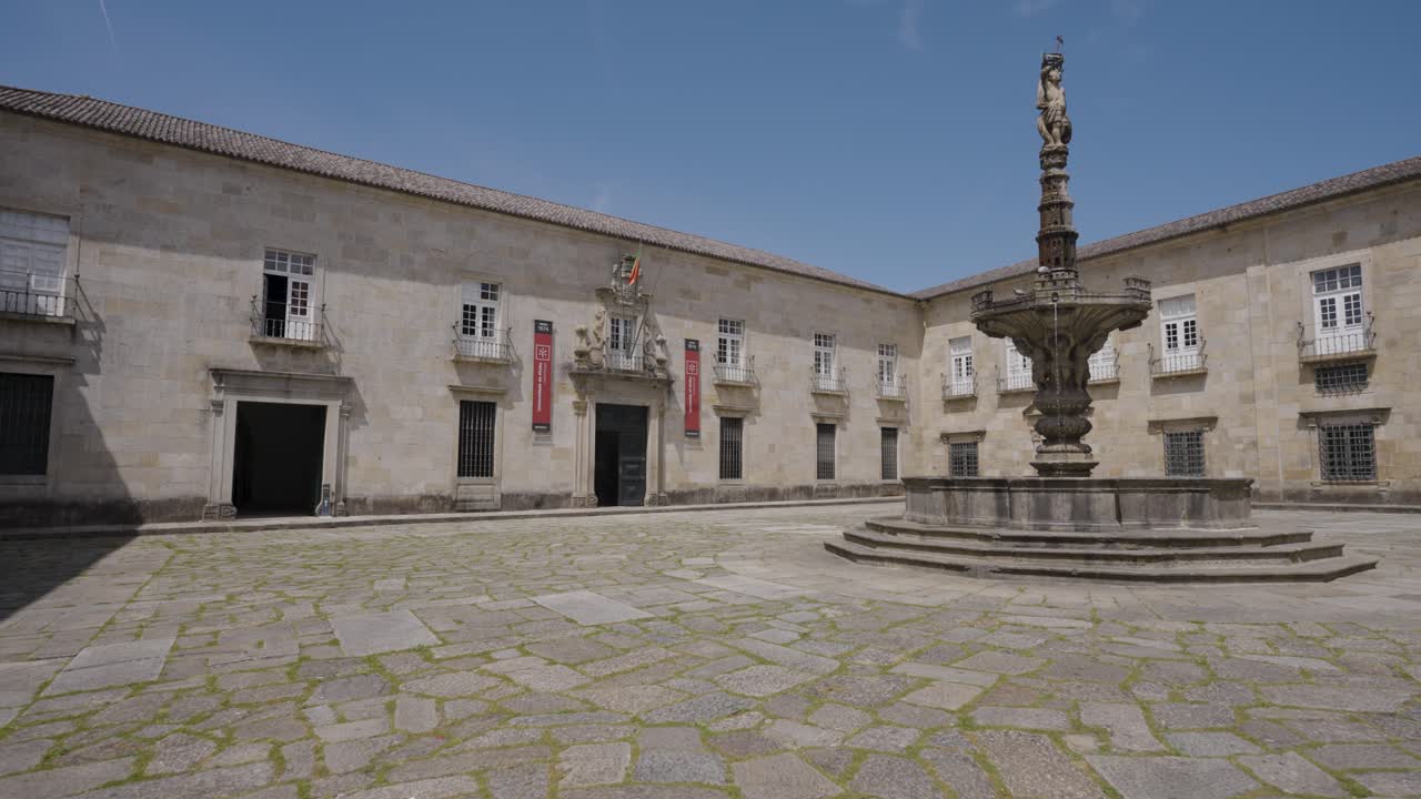 Baroque fountain crowned by a castels statue under a clear sky in front of the Reitoria University of Minho, Braga, Portugal.