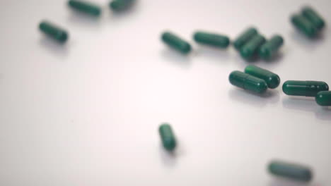 macro de pastillas verdes cayó sobre fondo blanco.