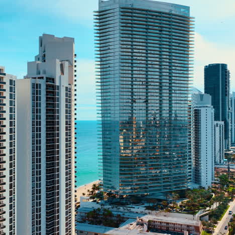 row of gorgeous modern skyscrapers on the coast of the atlantic ocean. sunny view of miami beach with beautiful azure waterscape at backdrop.