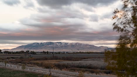 colorful sunrise illuminates the mountain before rising above the cloudscape in a windy time lapse